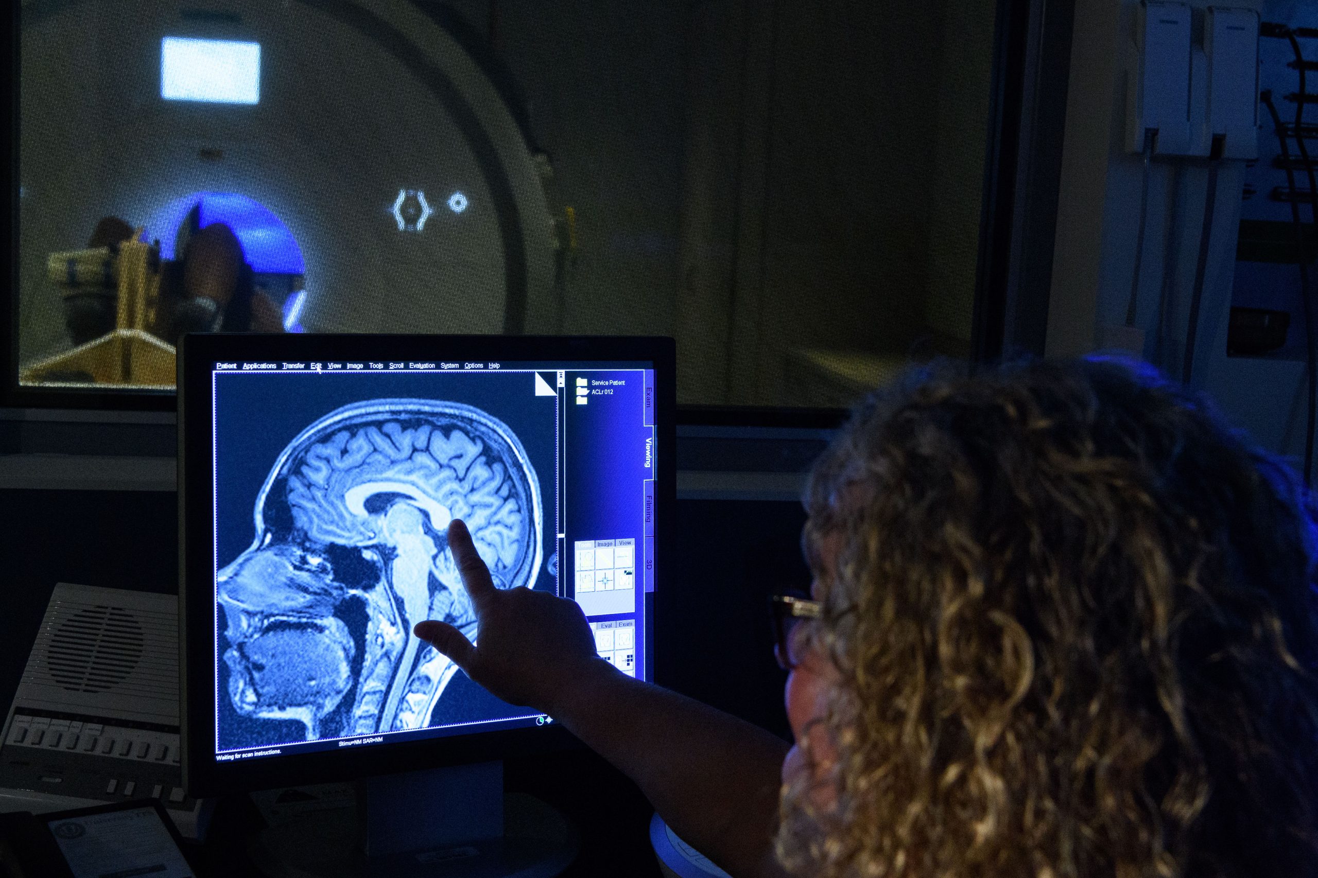 A scientist observes a functional MRI test in front of the scanner.